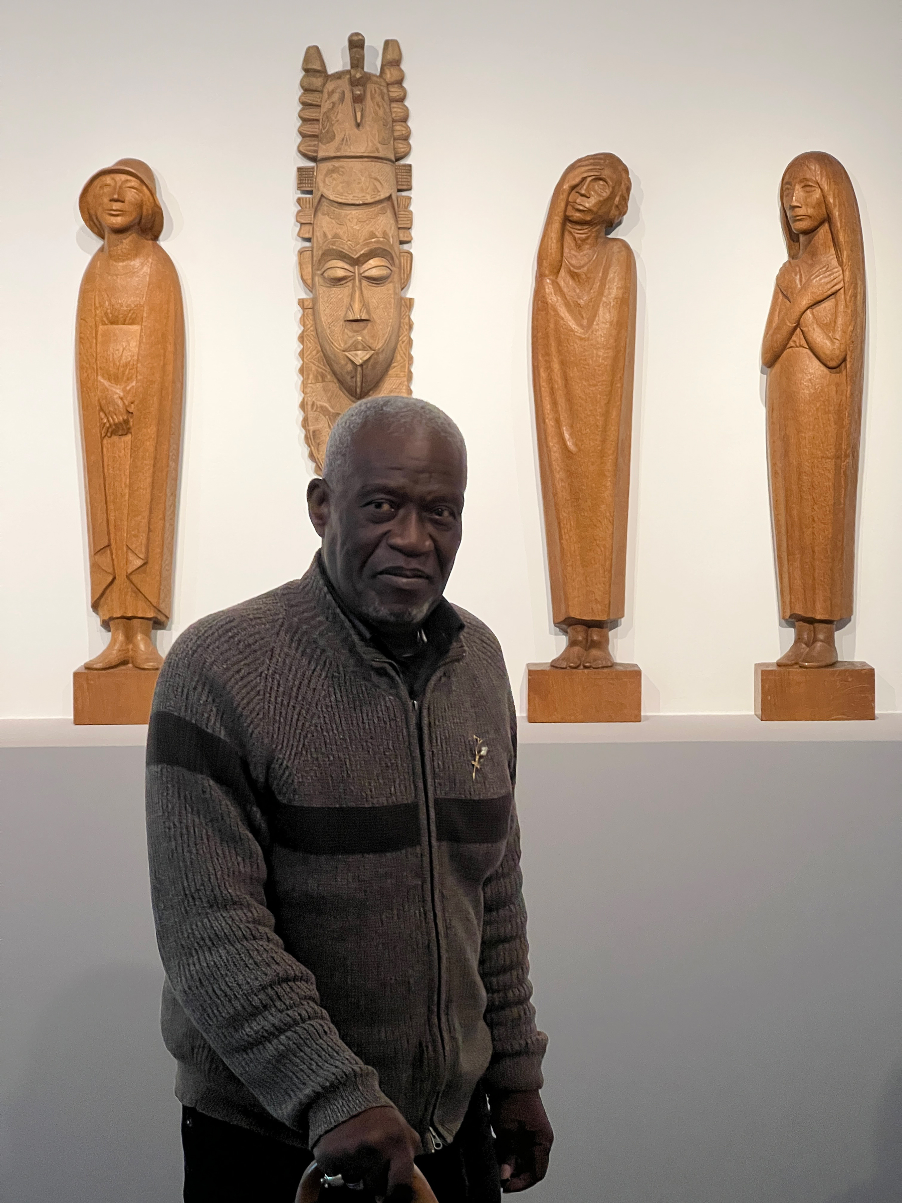 The artist Adéagbo stands in front of a series of Barlach sculptures of which he replaced one with a mask from Benin.