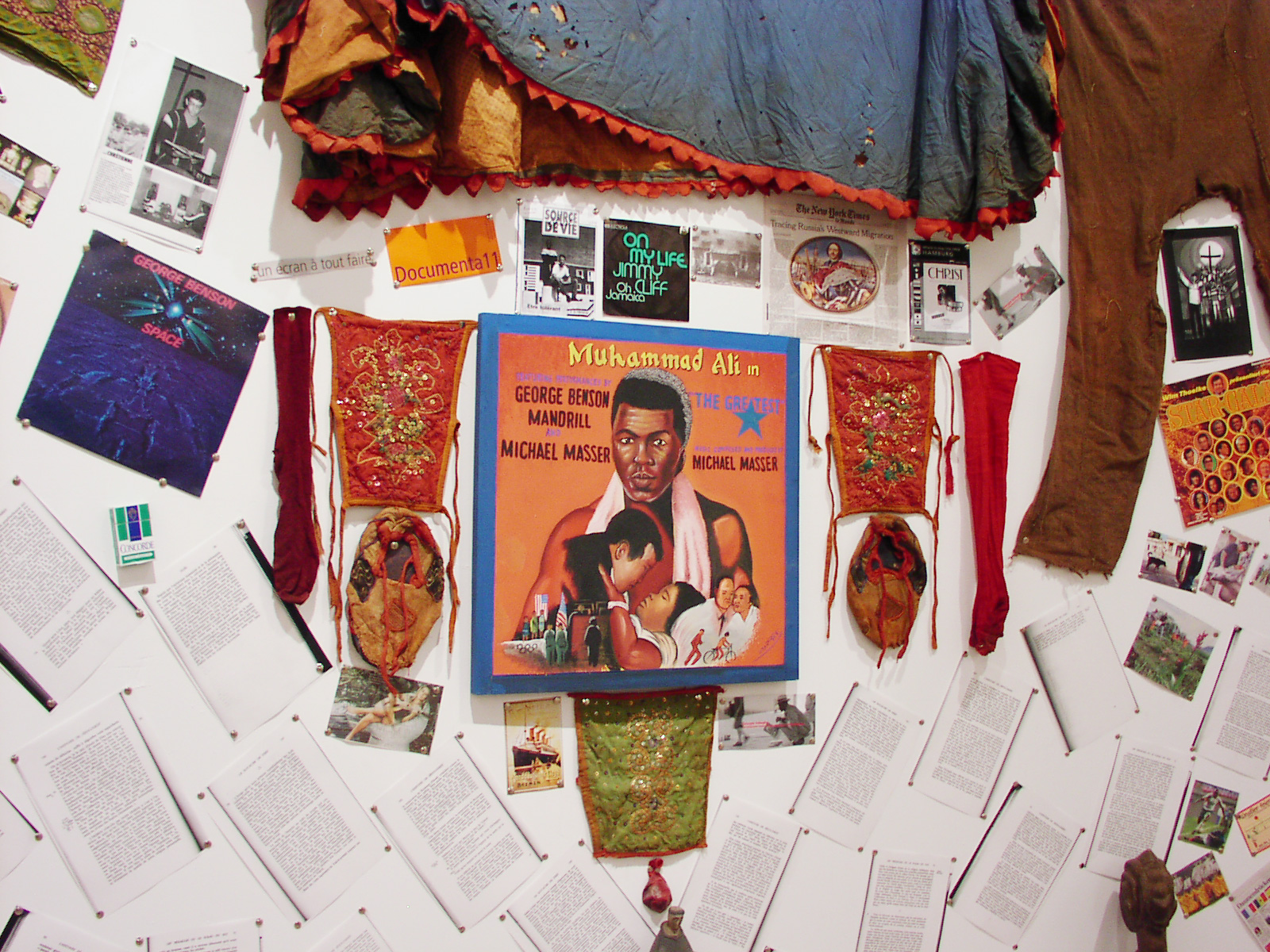 close up image of installation, painting of Mohammed Ali record cover, and ceremonial clothes from Benin