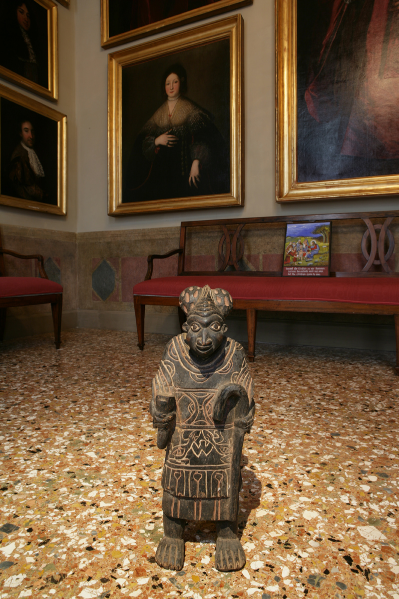 an african statue of a king stands in the center of a room in a venetian palazzo