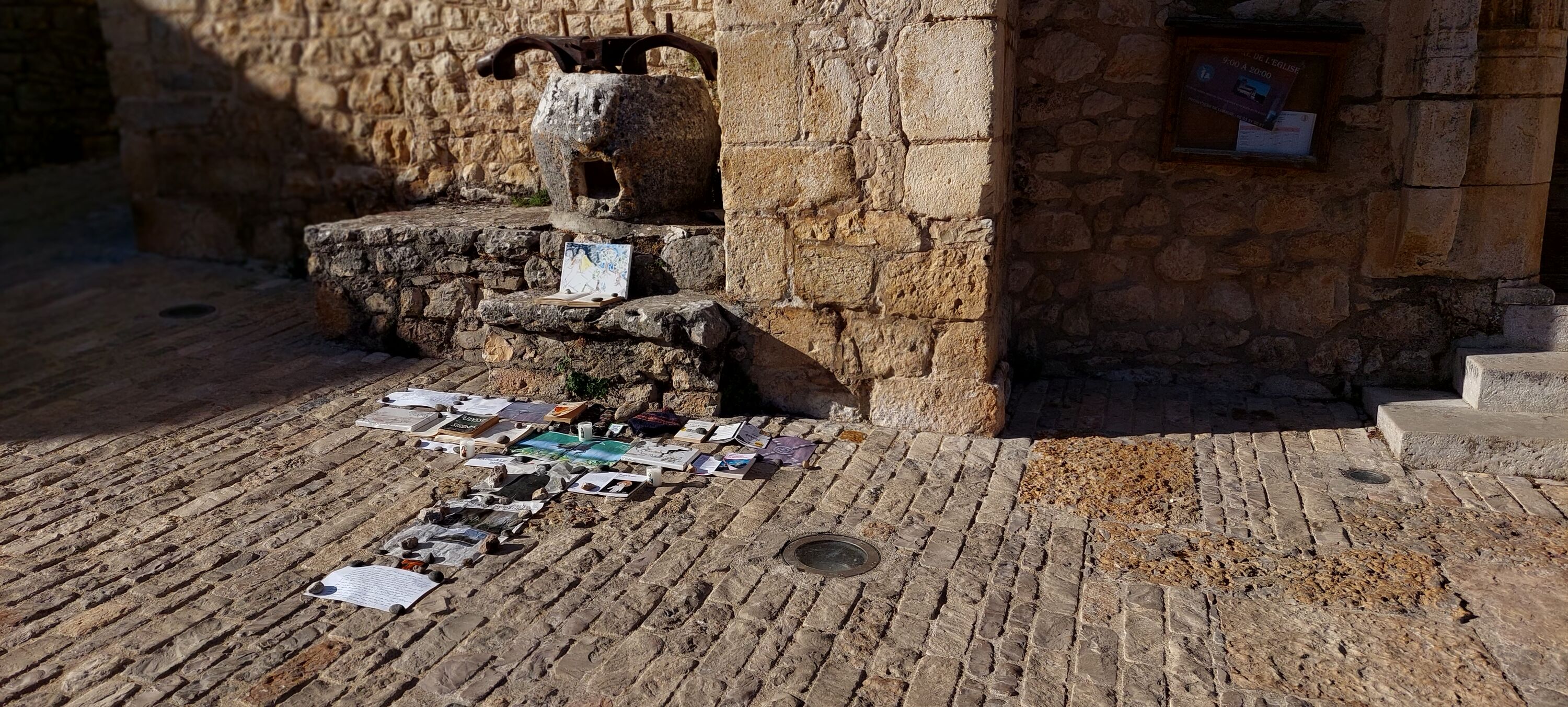 installation by Adéagbo on stone-floor in front of a church in St. Cirq-La-Popie