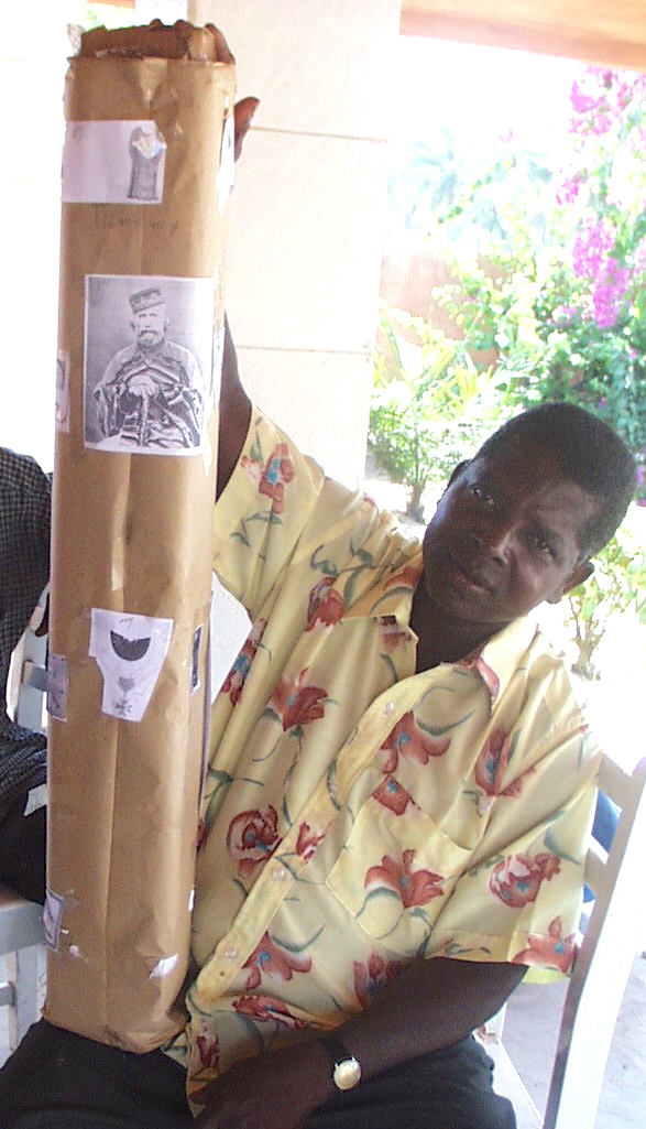 Artisan Kinigbè receives instructions for totempole from Georges Adéagbo. Photocopies pasted on a cardboard cylinder